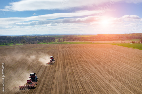 Aerial view of the sunset above the tractor harrowing the field
