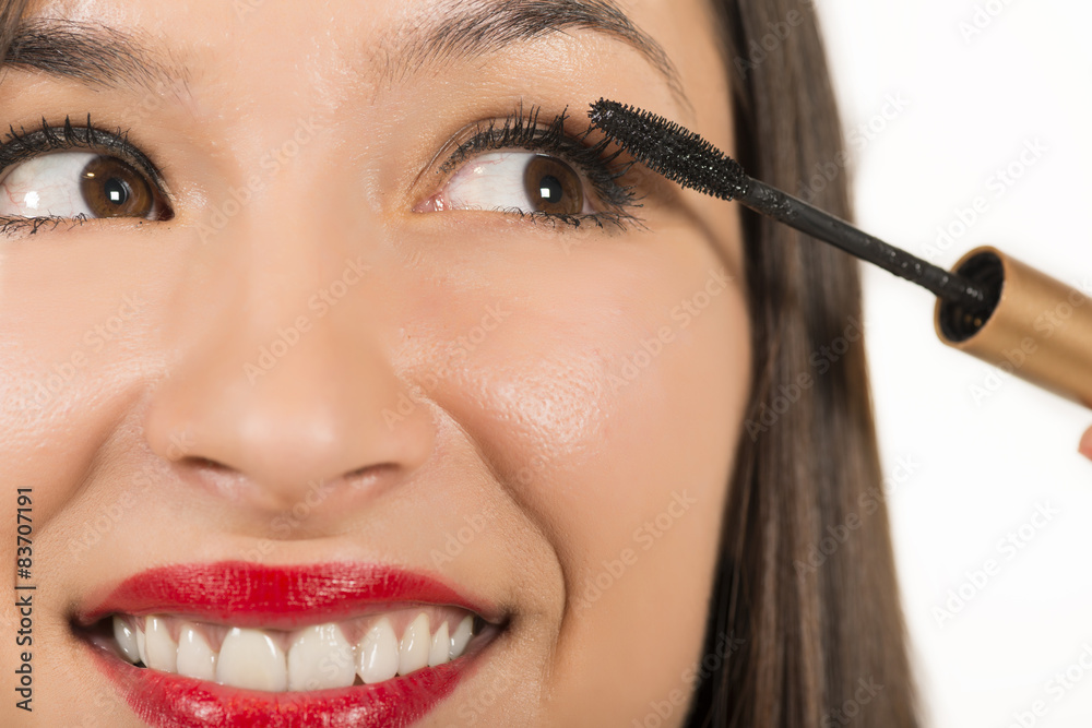 Close up portrait of beautiful young woman applying mascara