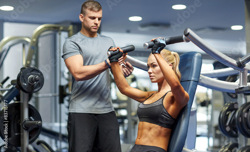 man and woman flexing muscles on gym machine photo