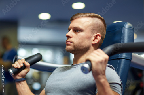 man exercising and flexing muscles on gym machine
