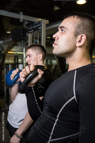 Kettlebell swing training of two young men in the gym