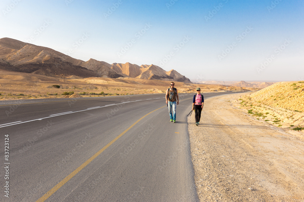 Couple walking desert asphalt road.