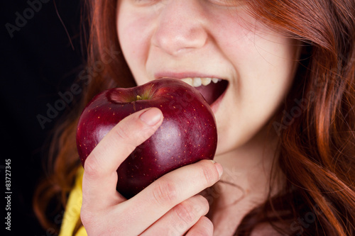 Young woman smiling and eating a fresh red apple
