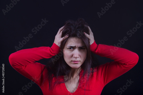 Stressed young women,student portrait, sad, bothered, holding hand on her head isolated on black background.