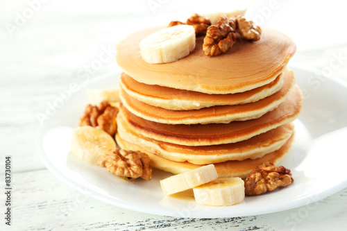 Delicious pancakes with banana on white wooden background