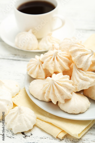 French meringue cookies with cup of coffee on white wooden backg