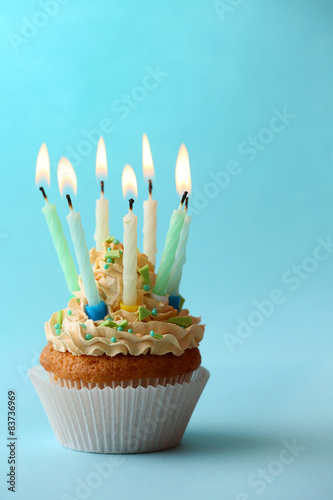 Birthday cupcake with candles on color background
