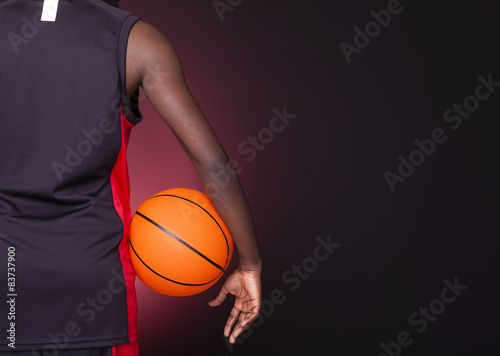 Back view of a basketball player holding a basketball against da