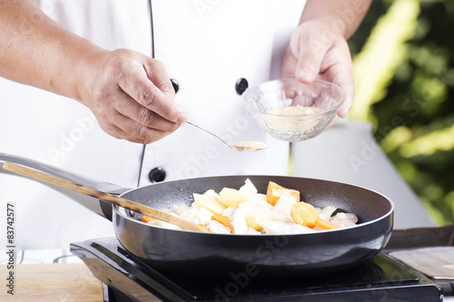 Chef putting the seasoning to the pan for cooking