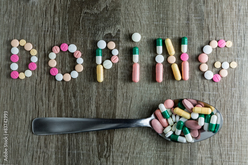 The word doping written with pills on a wooden background.