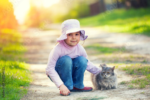 Little girl playing with cat in the countryside