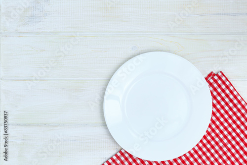 Empty plate and napkin on a white wooden background of a table.