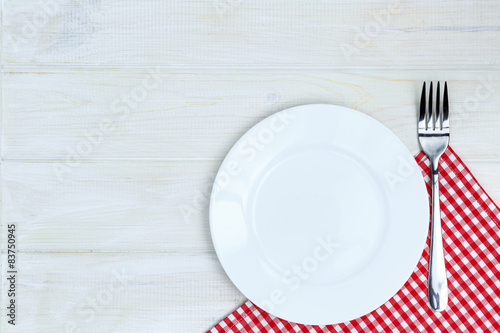 Empty plate and silverware over white wooden table background. V