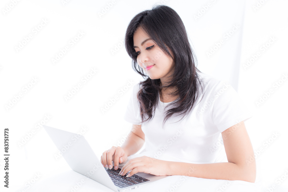 Smiling woman using a laptop while lying on her bed Smiling woman using a laptop while lying on her bed