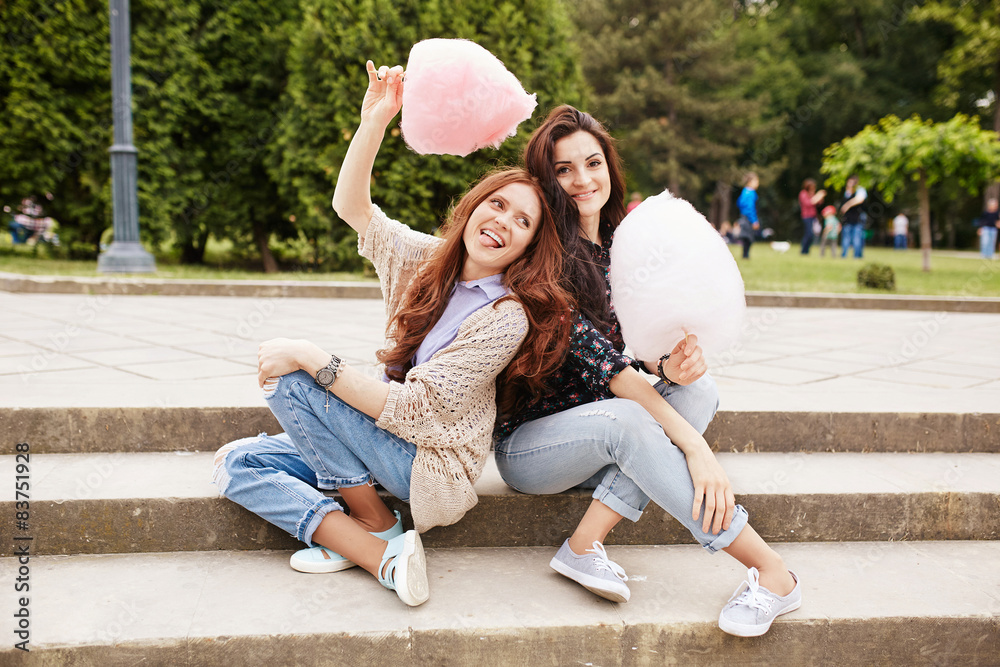 Two sisters eating cotton candy at the park
