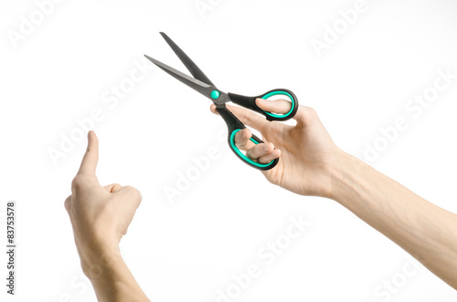 human hand holding a black scissors with blue accents in studio