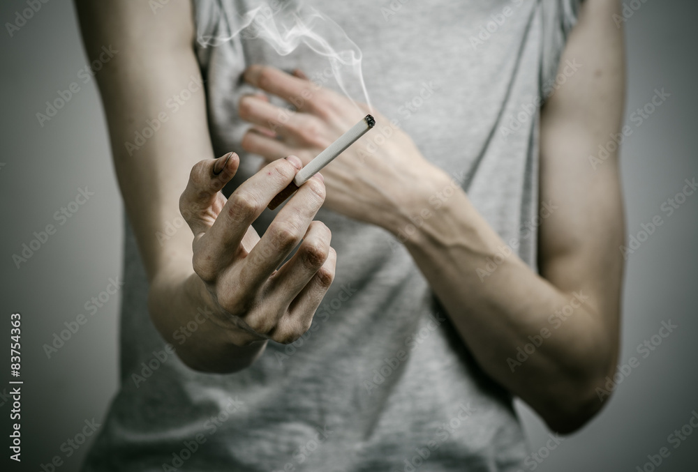 Fototapeta premium smoker holds the cigarette in his hand in the studio