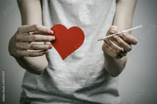 skinny dirty addict holding a syringe with a drug and red heart