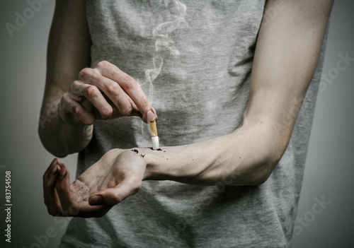 smoker puts his hand on the cigarette on a dark background © Parad St