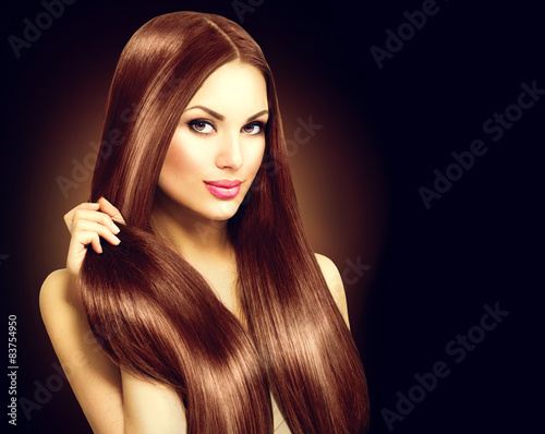 Beautiful brunette woman touching her long shiny straight hair