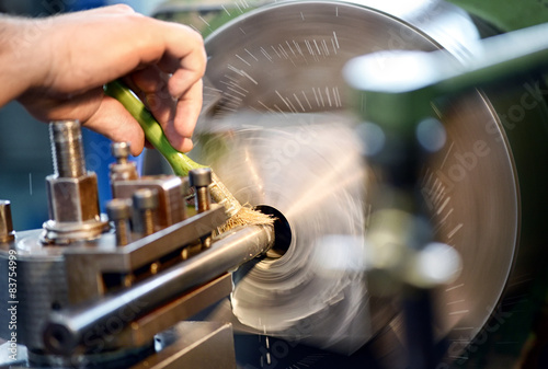 Fotografie Man placing lubricating oil on a lathe