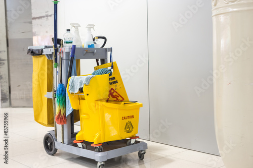 Yellow mop bucket and set of cleaning equipment photo