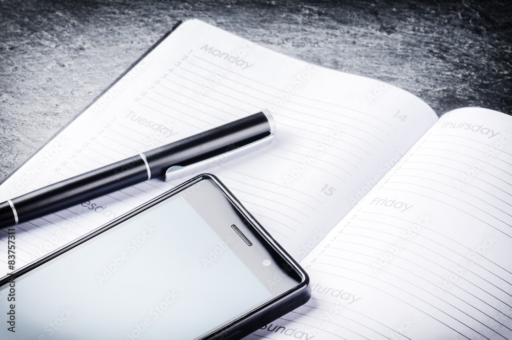 Business concept with agenda, mobile phone and pen