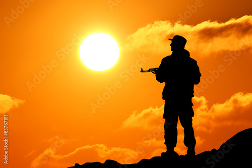 Silhouette shot of soldier holding gun with colorful sky 