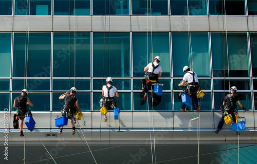 Team von kletternden Arbeitern auf Bürohaus Fassade