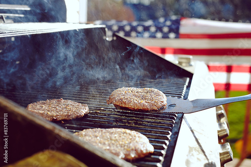 Burgers and hotdogs cooking over flames on grill
