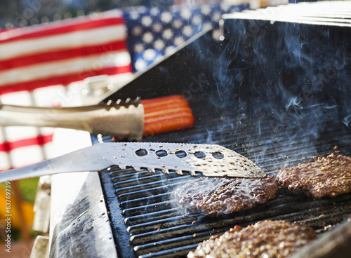 Burgers and hotdogs cooking over flames on grill
