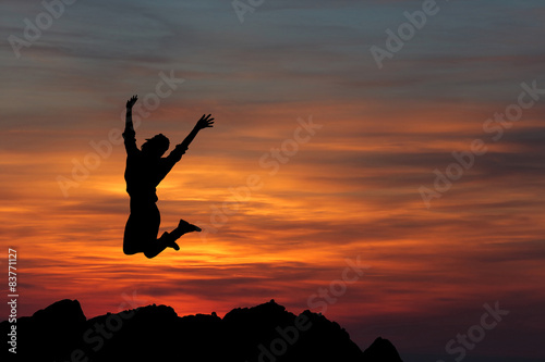 Happy woman jumping against beautiful sunset. Freedom concept.
