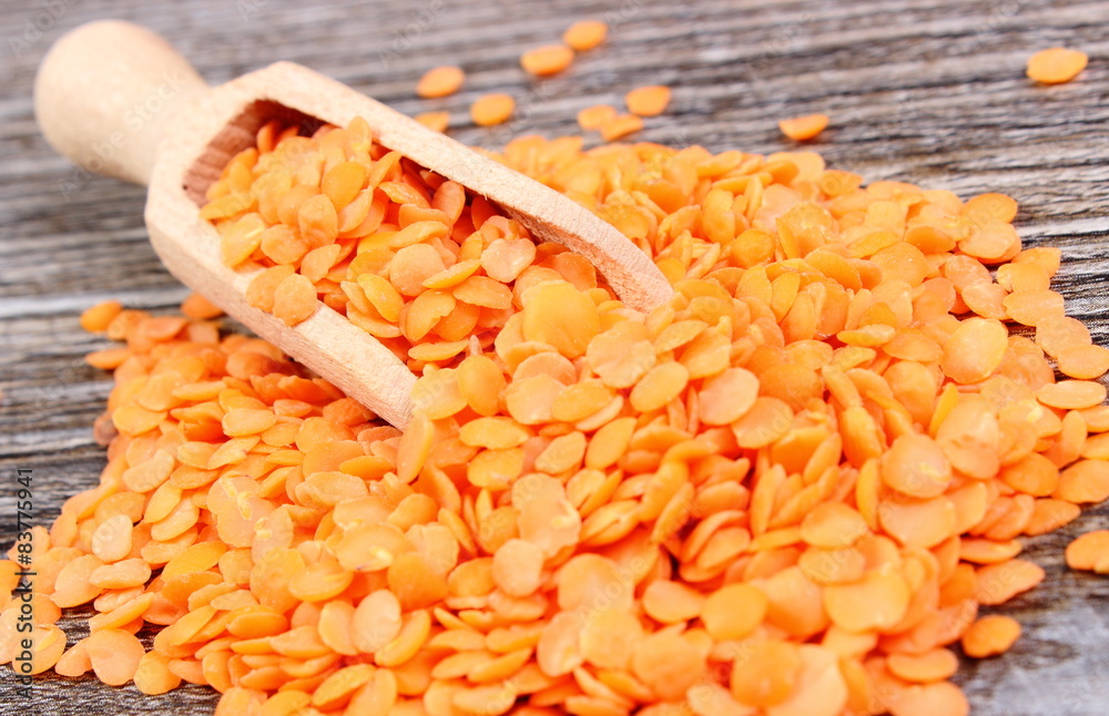 Heap of red lentil with spoon on wooden background Heap of red lentil with spoon on wooden background