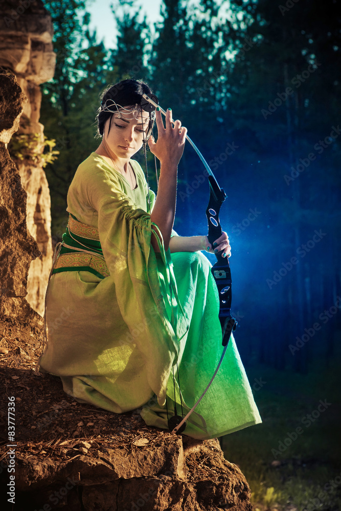 Elf woman with the magic bow on the rocks background. Elf woman with the magic bow on the rocks background.