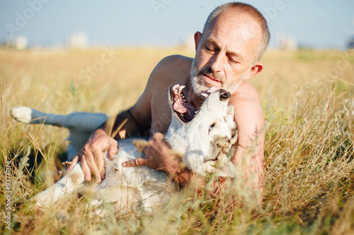 Old man plays with his dog Siberian Husky. Active recreation.