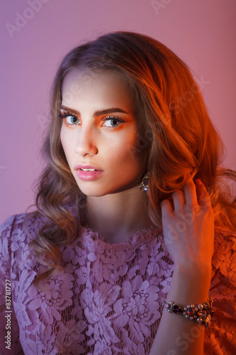 Beauty studio portrait of girl in pink dress with wavy hairstyle
