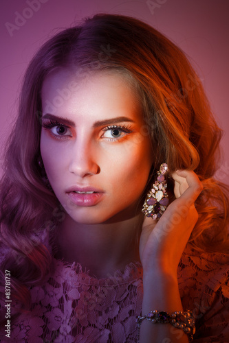 Beauty studio portrait of girl in pink dress with wavy hairstyle