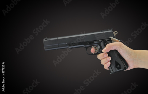 Hand holding gun isolated on black