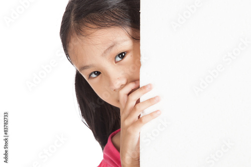 Little asian girl peeking behind a white board