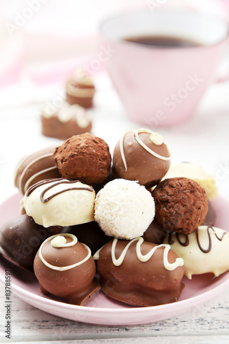 Chocolates in bowl on white wooden background