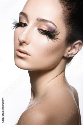 Girl with perfect skin and unusual makeup with feathers. Beauty face. Picture taken in the studio on a white background.