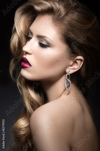 Beautiful woman with evening make-up  red lips and curls. Beauty face. Picture taken in the studio on a gray background.