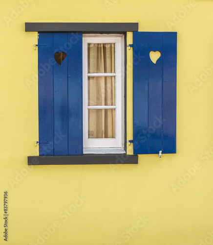 Detail of blue window with hearts and yellow wall