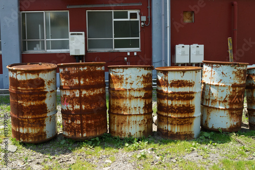 oil drums stacked together in a yard, 