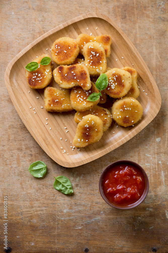 Bamboo tray with sesame chicken nuggets, rustic wooden surface Bamboo tray with sesame chicken nuggets, rustic wooden surface