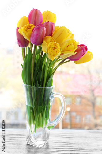 Fototapeta Naklejka Na Ścianę i Meble -  Beautiful bouquet of tulips in carafe on windowsill
