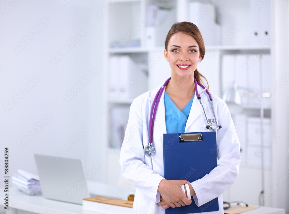 Smiling female doctor with a folder in uniform standing at Smiling female doctor with a folder in uniform standing at