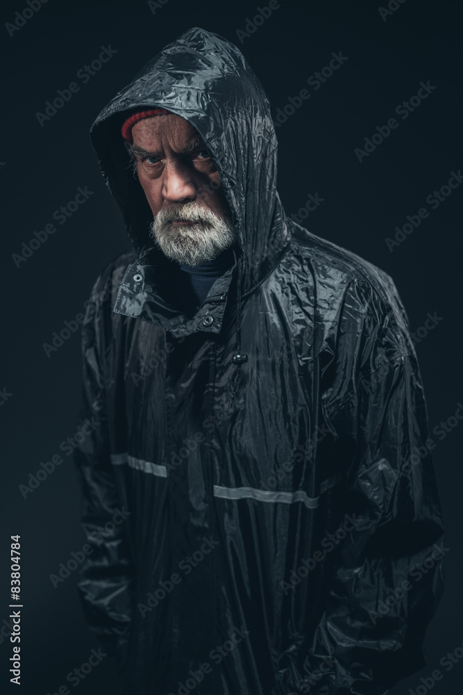 Serious Bearded Senior Man in Black Raincoat Serious Bearded Senior Man in Black Raincoat