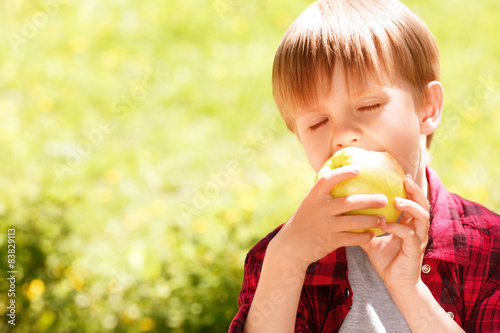 Close up of little boy biting off apple