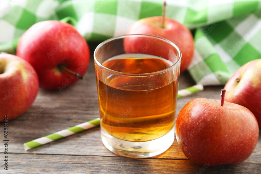 Glass of apple juice with apples on grey wooden background